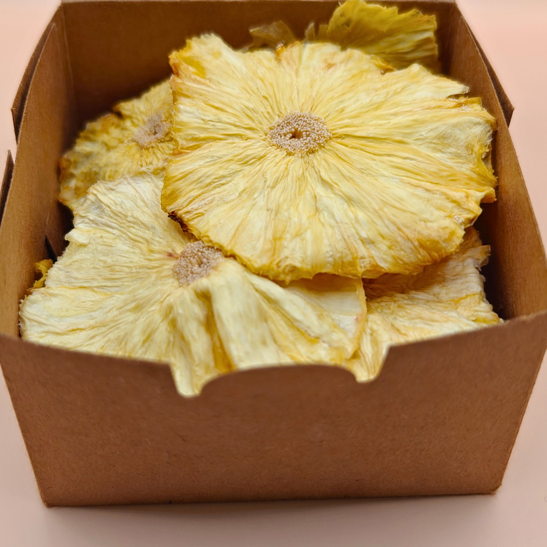 Open kraft box revealing slow-dried pineapple chips nestled on a paper doily, ready to snack or gift.
