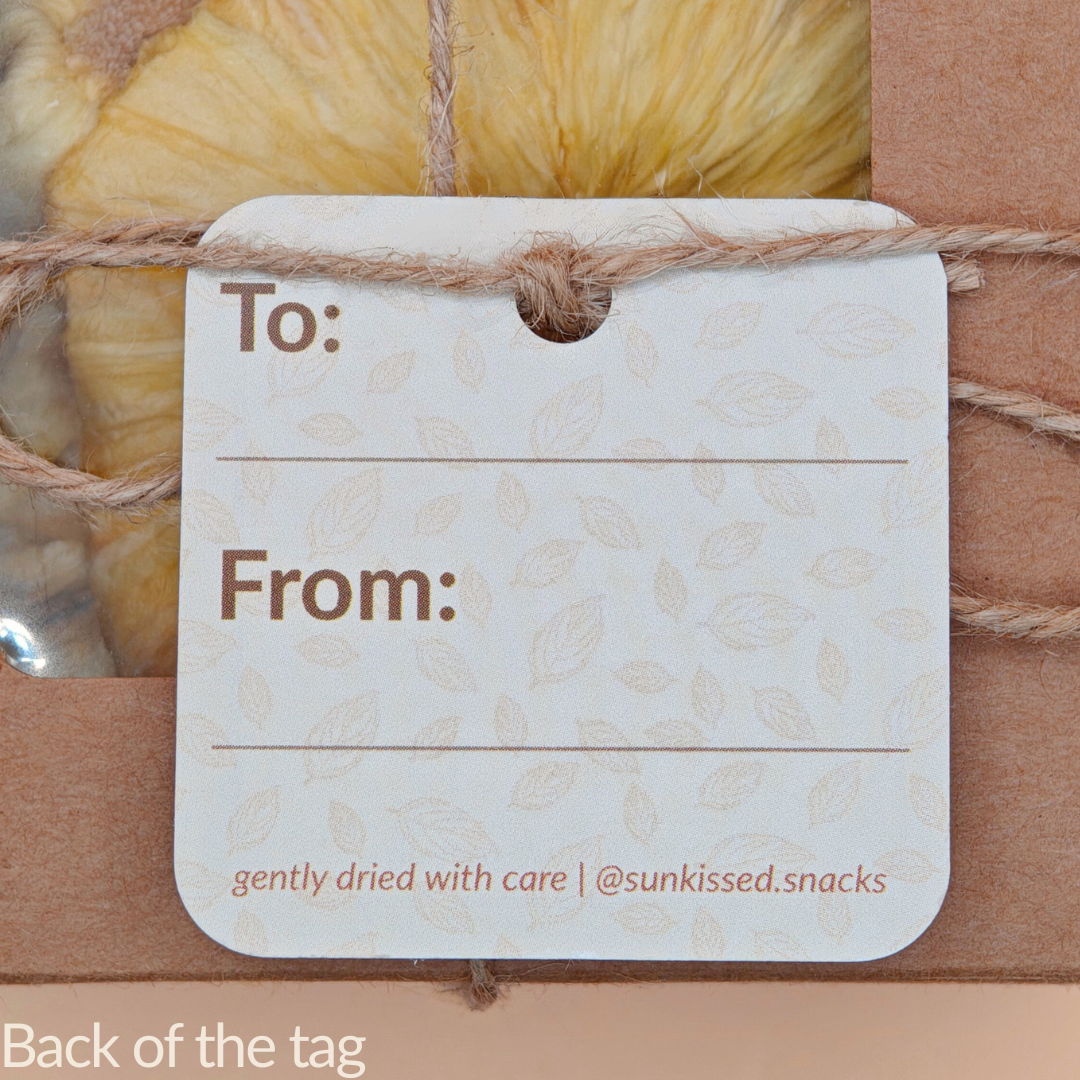 Back of the gift tag showing “To:” and “From:” fields over a leaf-pattern background and “@sunkissed.snacks” handle.